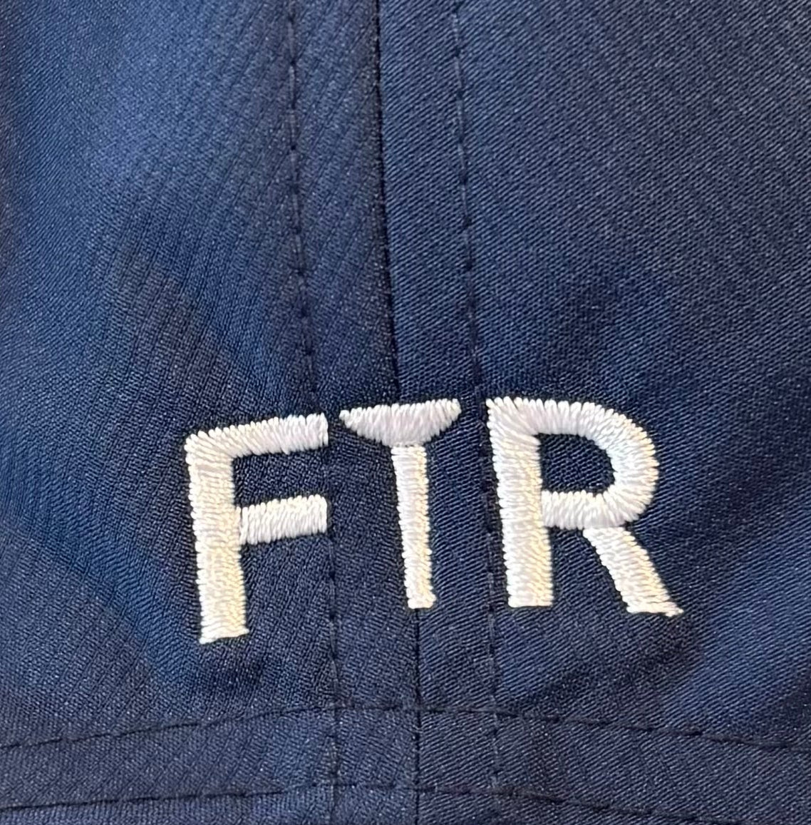 Close-up of a blue cap with 'FTR' embroidered on it.